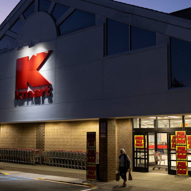 A Kmart in twilight, with “Store Closing Sale!” signs covering the entrance.