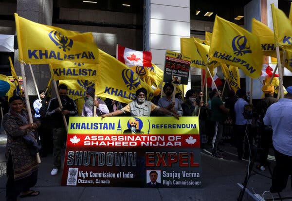 Protesters waving flags and hold a banner noting the assassination of a Sikh leader. 