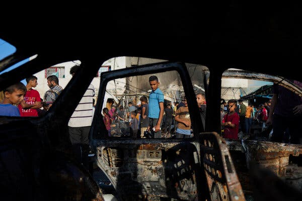 A person looks into the window of a charred vehicle. 