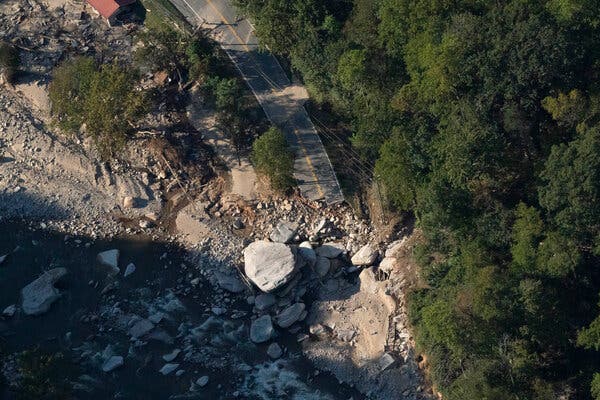 Part of a washed-out road is covered in boulders and other debris.