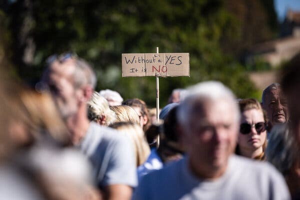 A demonstrator holds up a sign that reads “Without a yes, it is no.”